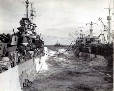 1945年1月丹佛（左）在海上通过管道从斯库尔基尔号油轮（USS Schuylkill AO-76）进行补油，画面中间远处的舰船是泰勒号驱逐舰