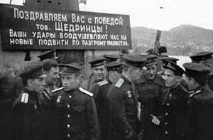S-56号潜艇的船员在波利亚尔内的欢迎会横幅上文字为：祝贺你们获得的胜利，谢德林的同志们！你们的行动鼓舞着我们，去立下粉碎法西斯的新功勋。
