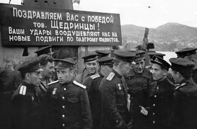 S-56号潜艇的船员在波利亚尔内的欢迎会横幅上文字为：祝贺你们获得的胜利，谢德林的同志们！你们的行动鼓舞着我们，去立下粉碎法西斯的新功勋。